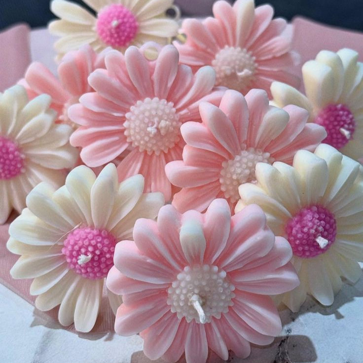 Pink and white flower-shaped candles on a marble surface