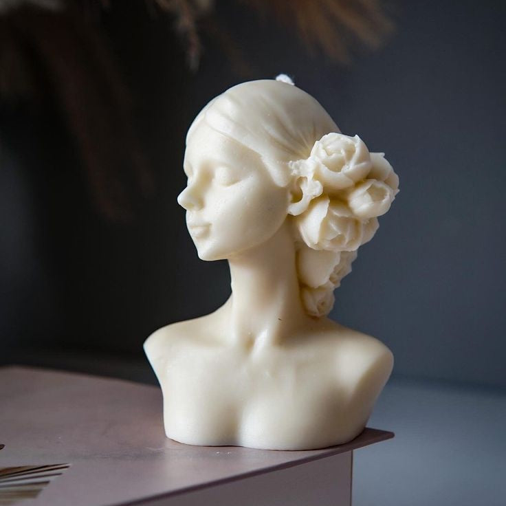 White marble bust of a woman with a flower in her hair on a dark background