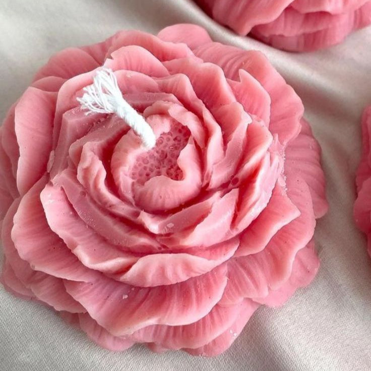 Pink flower-shaped candles on a light fabric background